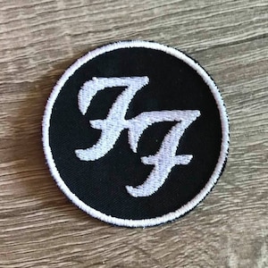 May include: Black and white embroidered patch with the letters "FF" in a stylized font, surrounded by a white circle on a black background.
