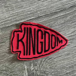 May include: Red fabric arrow patch with black embroidered text that reads "KINGDOM".
