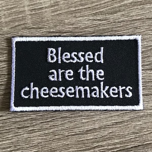 May include: Black and white embroidered patch with the text "Blessed are the cheesemakers".