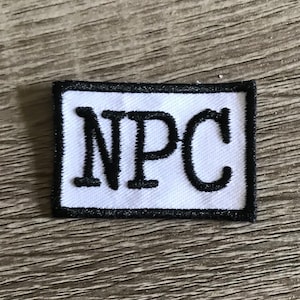 May include: White fabric patch with a black border and the word "NPC" in black lettering.