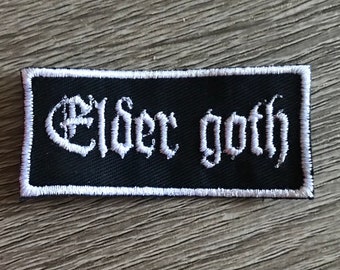 May include: Black embroidered patch with white stitching. The patch reads "Elder Goth" in a gothic font.