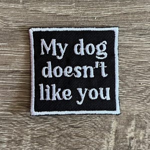 May include: Black and white embroidered patch with the text "My dog doesn't like you".
