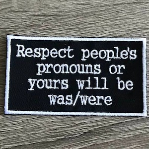 May include: Black and white embroidered patch with the text "Respect people's pronouns or yours will be was/were"