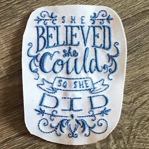 May include: White fabric with blue embroidered text that reads "She believed she could so she did".