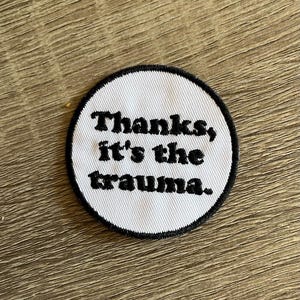 May include: White round embroidered patch with black text that reads "Thanks, it's the trauma."