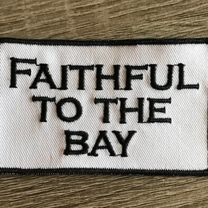 May include: White embroidered patch with black stitching. The patch reads "Faithful to the Bay".