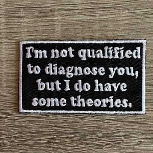 May include: Black and white embroidered patch with the text "I'm not qualified to diagnose you, but I do have some theories."