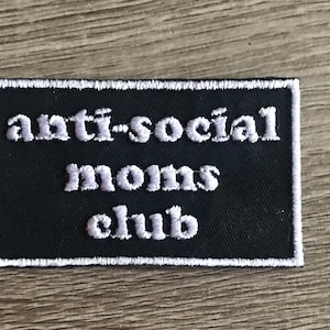May include: White embroidered patch on black fabric with the text "anti-social moms club".