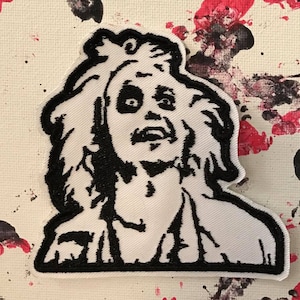 May include: Black and white embroidered patch of a character with wild hair and a shocked expression. The character is wearing a white shirt.