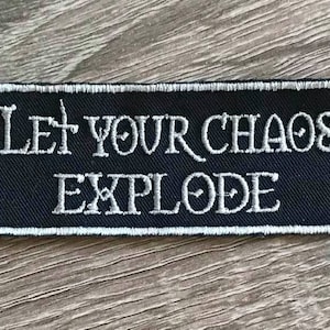 May include: Black embroidered patch with white stitching. The patch reads "Let Your Chaos Explode".