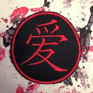 May include: A black and red embroidered patch with the Chinese character for "love" in red.