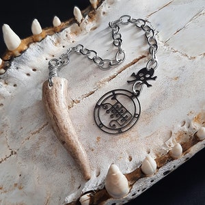 May include: A silver chain necklace with a skull charm and a circular pendant inscribed with the words "I love you". The pendant is attached to a small antler point.