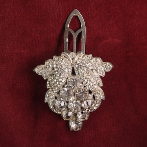 May include: A silver hair comb with a decorative design of a cluster of crystal rhinestones in the shape of a flower.