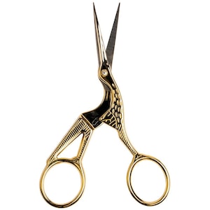 May include: Gold-colored embroidery scissors with a crane design. The scissors have a detailed crane head and body, with a small gem accent. The blades are silver and sharp, and the finger holes are round.