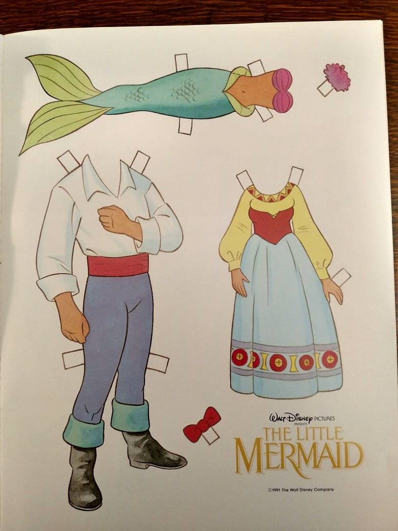 May include: Paper doll set featuring Ariel and Prince Eric from Disney's The Little Mermaid. The set includes a mermaid tail, a dress, a shirt, trousers, and a bow tie. The paper dolls are ready to be cut out and played with.