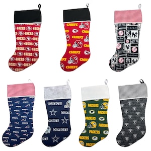 May include: Set of six Christmas stockings featuring various NFL team logos. The stockings are red, green, blue, black, and white with a variety of patterns. The logos include the 49ers, Chiefs, Patriots, Cowboys, Packers, and Jets.