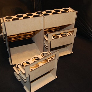 May include: A set of unfinished, interlocking wooden organizers. Each unit features multiple circular openings and rectangular compartments. The natural wood color contrasts against the dark background, highlighting the geometric design.