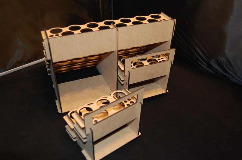 May include: A set of unfinished, interlocking wooden organizers. Each unit features multiple circular openings and rectangular compartments. The natural wood color contrasts against the dark background, highlighting the geometric design.