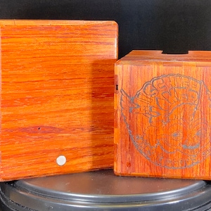 May include: Two wooden boxes, one with a plain surface and the other with an engraved design of a creature with wings and the text "GINGER HYDE" around it.