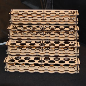 May include: A multi-tiered, wooden organizer with numerous circular openings. The natural wood-toned structure is designed to hold small items, possibly paint bottles or craft supplies. The stacked design provides ample storage space.