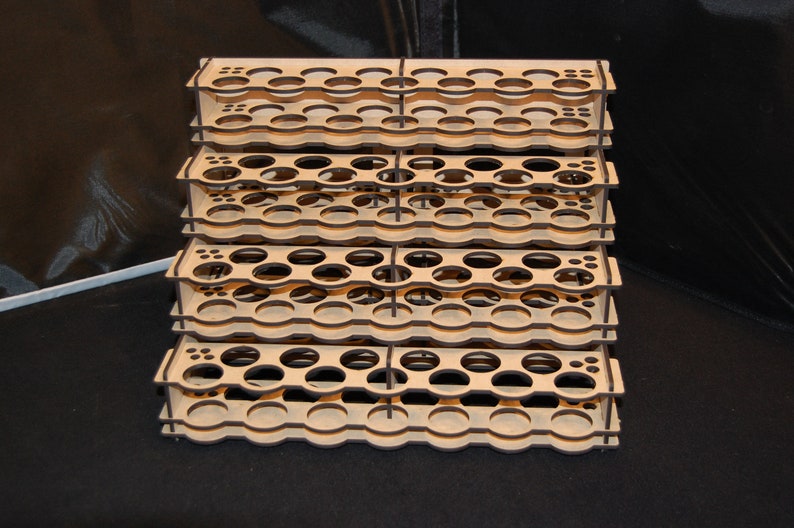 May include: A multi-tiered, wooden organizer with numerous circular openings. The natural wood-toned structure is designed to hold small items, possibly paint bottles or craft supplies. The stacked design provides ample storage space.