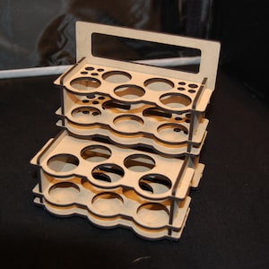 May include: A three-tiered wooden organizer with multiple circular and small rectangular openings. The top tier has a handle. The organizer is made of light-colored wood and appears to be designed for holding small items, such as paint bottles or art supplies.