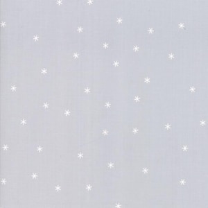 May include: A light gray fabric with a repeating pattern of small, white snowflakes. The snowflakes are evenly spaced across the surface of the fabric, creating a wintery or holiday theme.