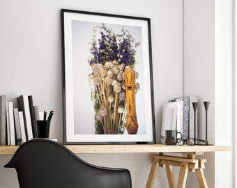 Peut inclure: Une impression encadrée d'une flûte à bec en bois avec des fleurs séchées dans un vase. L'impression est accrochée à un mur blanc au-dessus d'un bureau en bois avec une chaise noire.
