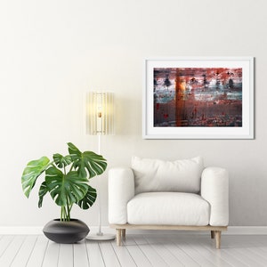 May include: A white armchair with a white lamp and a green plant in a black pot. A framed abstract painting with red, blue, and brown colors hangs on the wall behind the armchair.