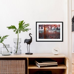 May include: A black and white abstract painting in a black frame hangs on a white wall above a wooden shelf with a black crane figurine, two clear glass vases with green plants, and a white clock.