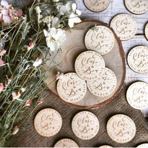 May include: Wooden save the date magnets with the text "Save the Date Clare & Ben 30th March 2018" in a cursive font.