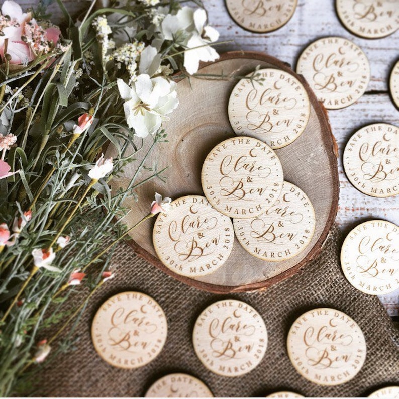 May include: Wooden save the date magnets with the text "Save the Date Clare & Ben 30th March 2018" in a cursive font.