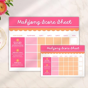 Puede incluir: Dos hojas de puntuación de Mahjong rectangulares con encabezado rosa, borde festoneado naranja y secciones de cuadrícula blancas para nombres de jugadores, puntuaciones de juegos y totales, incluyendo instrucciones de puntuación.