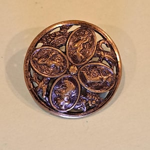 May include: A round copper-toned button featuring an openwork design with four distinct oval medallions. Each medallion displays a raised relief figure, including a horse and human forms, set within a circular frame with intricate filigree details.