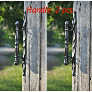 以下が含まれることがあります： 装飾的なデザインが施された黒い金属製のドアノブが2つ。ノブは木製のドアに取り付けられています。画像には「Handle: 2 pcs.」というテキストが表示されています。