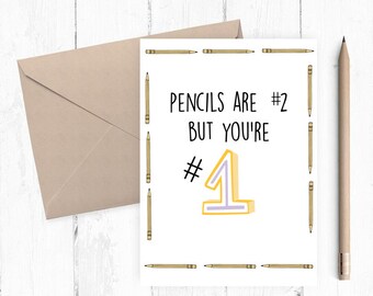 May include: A white card with a black border of pencils. The card says "Pencils are #2 but you're #1" with a large yellow number one with a purple outline.
