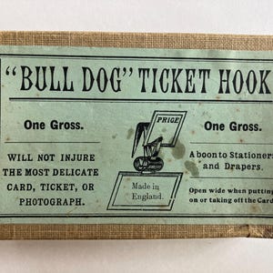 May include: Vintage "Bull Dog" Ticket Hook box with text in black on a light green background. The box has a tan border and features the text "One Gross" and "Made in England."