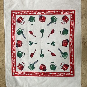 May include: A white square kitchen towel featuring a red border patterned with various cooking utensils. The center displays a repeating print of red and green kitchenware, including kettles, saucepans, toasters, and ladles, arranged in a grid.