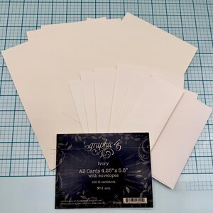 May include: A pack of six sets of ivory A2 cards with envelopes. Each set contains 100 cards and envelopes. The cards are 10.8 cm by 14 cm and are made of 100 lb cardstock. The packaging features the graphic 45 logo.