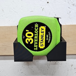 May include: A green and black tape measure holder with a 30' Stanley Leverlock tape measure. The tape measure is labeled "30-997 Made in U.S.A."