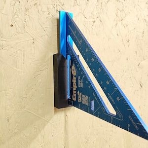 May include: A blue and black combination square with a black magnetic holder. The square has markings in degrees and inches. The text "True" and "Empire" are printed on the square.
