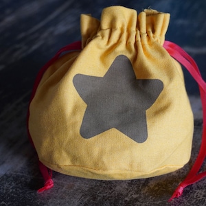 May include: A yellow drawstring bag with a gray star design and red drawstrings.