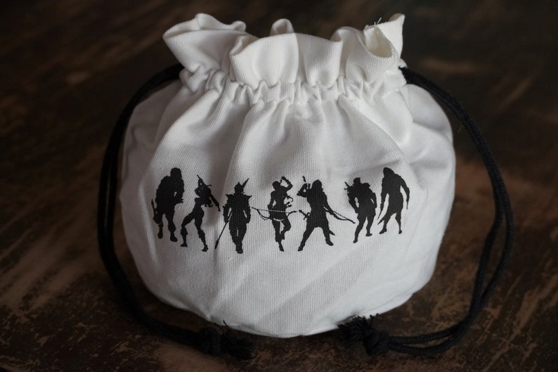 Pode incluir: Saco de cord&atilde;o branco com silhuetas pretas de figuras na frente. As figuras est&atilde;o em linha e parecem ser personagens de um jogo de fantasia.