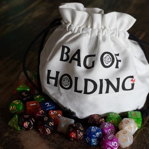Pode incluir: Uma bolsa de tecido branca com o texto "Bag of Holding" impresso nela. A bolsa est&aacute; cheia de dados coloridos, incluindo vermelho, verde, azul e branco.
