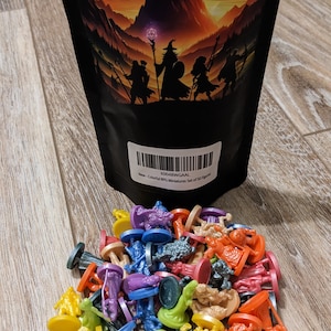 Pode incluir: Um saco com 50 figuras em miniatura de pl&aacute;stico coloridas para jogos de RPG. O saco tem um fundo preto com uma ilustra&ccedil;&atilde;o de fantasia de uma cordilheira, um mago e um drag&atilde;o. O saco tem um c&oacute;digo de barras e o texto "Colorful RPG Miniatures Set of 50 Figures".