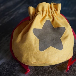 Pode incluir: Uma bolsa de cord&atilde;o amarela com um design de estrela cinza. A bolsa tem um cord&atilde;o vermelho.