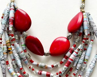 May include: Multi-strand necklace featuring red and white paper beads, silver beads, and red stone beads.