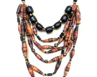 May include: Multi-strand necklace with black and orange paper beads. The necklace features a layered design with multiple strands of beads.