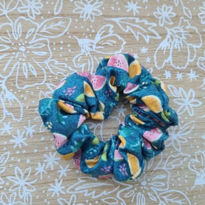 Op de afbeelding: Een tealblauwe scrunchie met een watermeloen- en geel fruitprint.