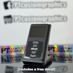 May include: Black and gray Air Lift Performance controller with a carbon fiber design. The controller has a screen and buttons. The image includes the text "AIRLIFT PERFORMANCE" and "[includes a free decal]"